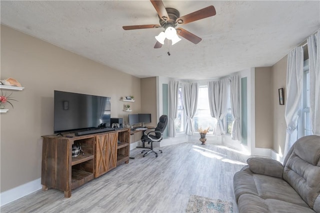 office space with baseboards, light wood-style floors, ceiling fan, and a textured ceiling