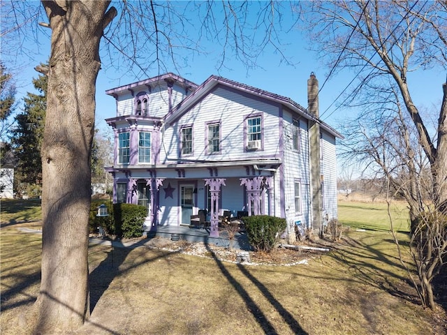 view of front of home featuring covered porch, a chimney, and a front lawn