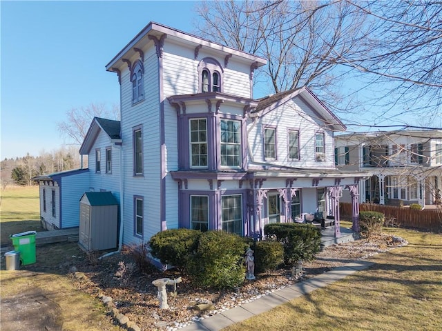 italianate home with a front yard, a porch, and fence