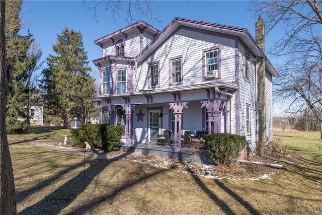 view of front of house with a front yard, covered porch, and a chimney