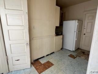 kitchen with light floors, a wainscoted wall, and freestanding refrigerator