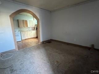 spare room with baseboards, arched walkways, and crown molding