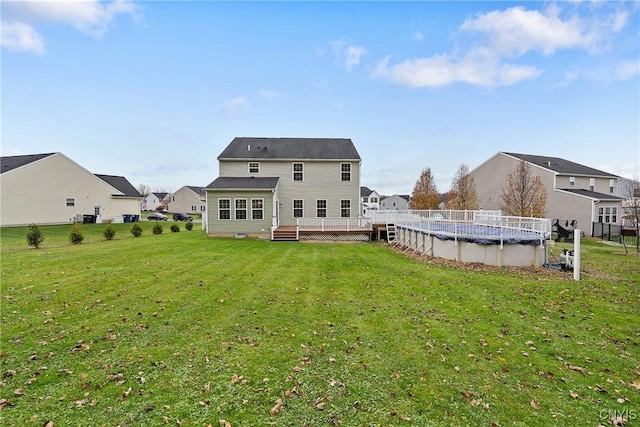 rear view of house featuring a covered pool and a lawn