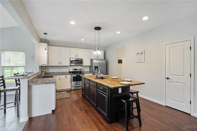 kitchen with a breakfast bar area, appliances with stainless steel finishes, dark cabinetry, white cabinets, and a sink