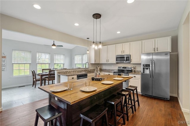 kitchen with stainless steel appliances, plenty of natural light, a peninsula, and white cabinets