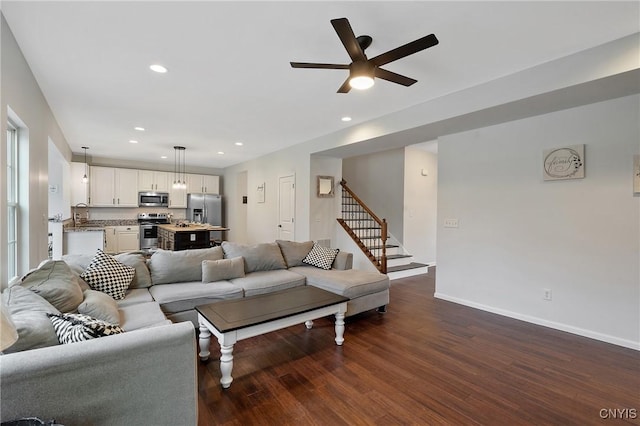 living area featuring ceiling fan, baseboards, stairway, recessed lighting, and dark wood-style flooring