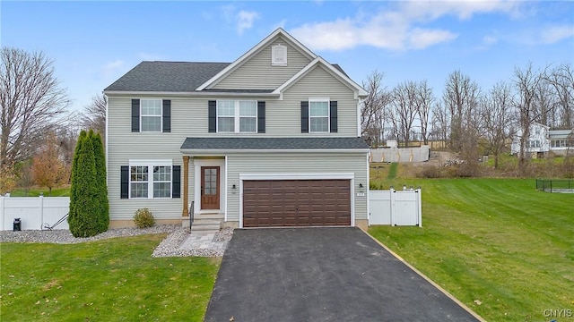 traditional-style home featuring aphalt driveway, an attached garage, a front yard, and fence