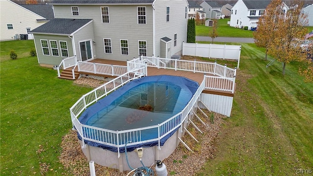 view of swimming pool with a lawn, a deck, and fence