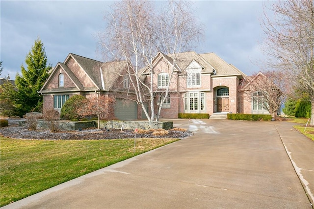 view of front of house featuring concrete driveway, an attached garage, brick siding, and a front lawn