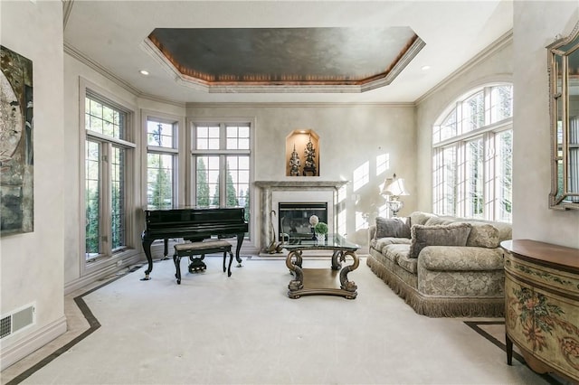 sitting room with a tray ceiling, a premium fireplace, visible vents, and crown molding