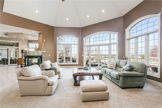 carpeted living area with a premium fireplace, baseboards, high vaulted ceiling, and a healthy amount of sunlight