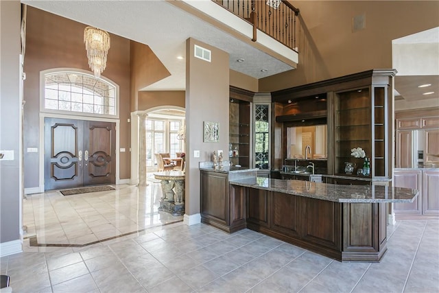 interior space with decorative columns, baseboards, visible vents, and a towering ceiling