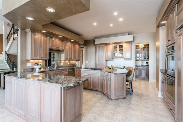 kitchen featuring stone countertops, stainless steel appliances, a peninsula, and a sink