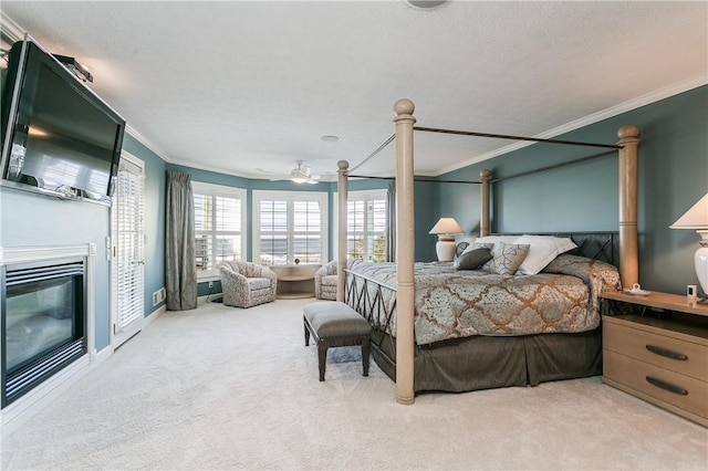 bedroom with baseboards, a glass covered fireplace, carpet flooring, and crown molding