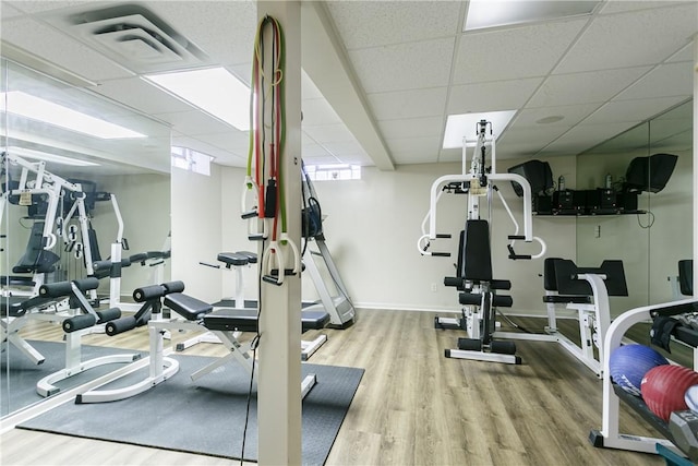 workout area with wood finished floors, visible vents, a drop ceiling, and baseboards