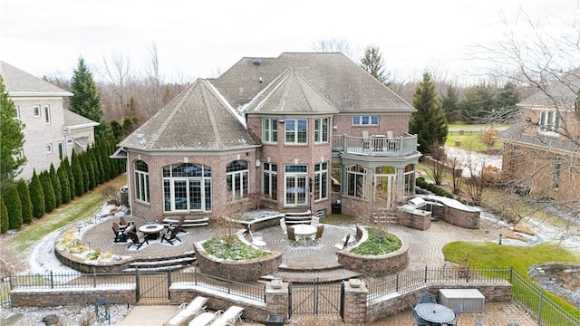 rear view of property with brick siding, an outdoor fire pit, roof with shingles, a fenced backyard, and a patio area