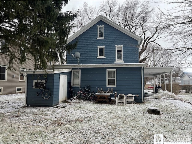 snow covered back of property featuring a carport