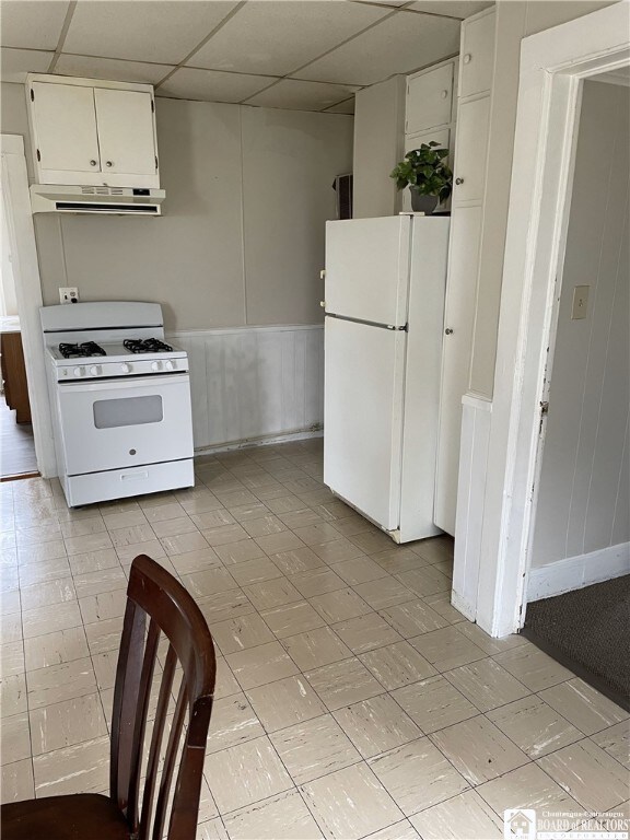 14 Moore Ave, Pomfret, NY 14063 - kitchen featuring white appliances, a paneled ceiling, a wainscoted wall, white cabinetry, and range hood