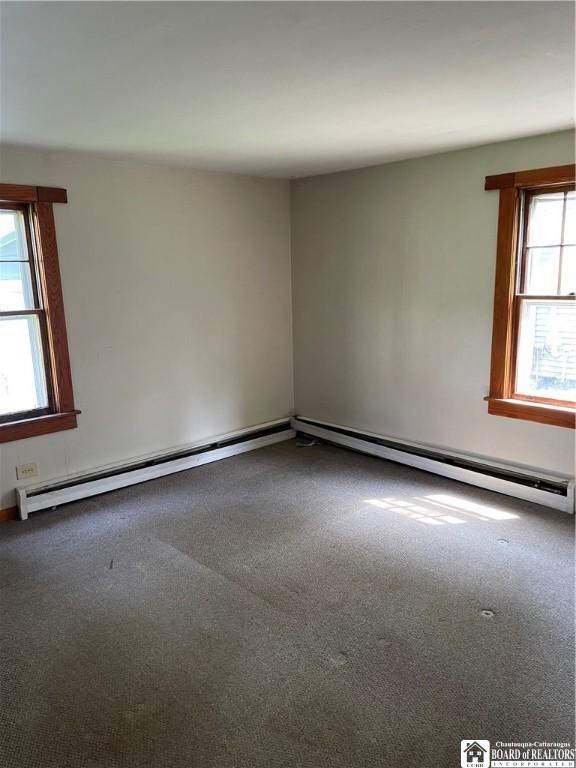 14 Moore Ave, Pomfret, NY 14063 - empty room featuring plenty of natural light, carpet, and a baseboard heating unit
