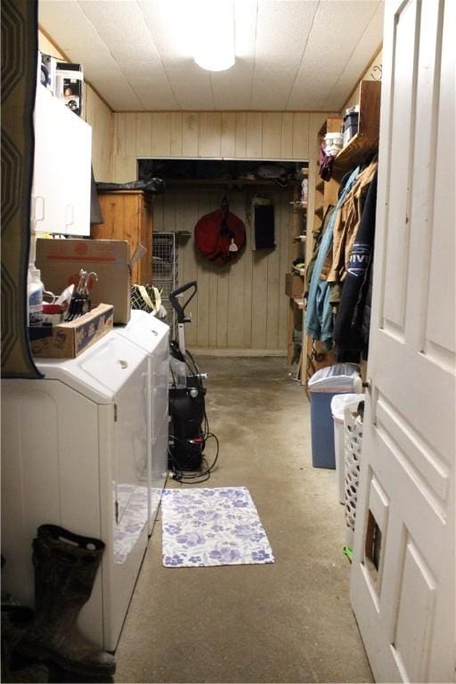 washroom with cabinet space, wooden walls, and independent washer and dryer