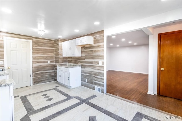 kitchen featuring light wood-type flooring, white cabinetry, recessed lighting, baseboards, and light stone countertops