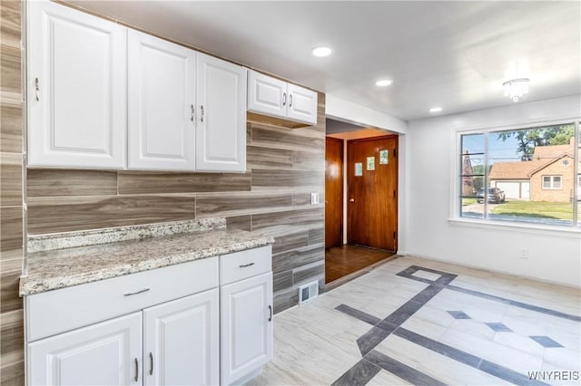 kitchen featuring white cabinetry, light stone counters, recessed lighting, and visible vents