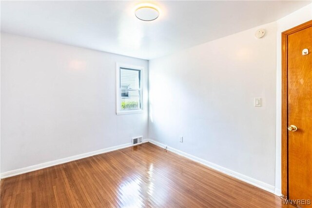 empty room with visible vents, baseboards, and wood finished floors