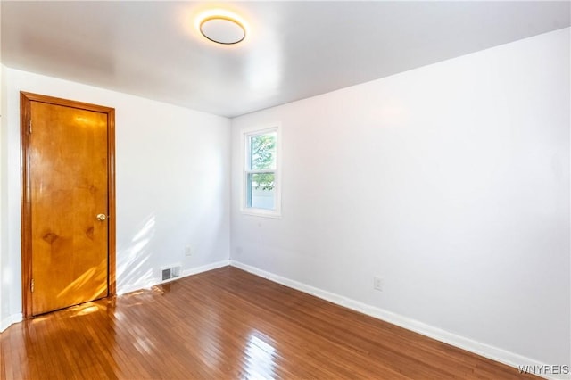 spare room with hardwood / wood-style floors, baseboards, and visible vents