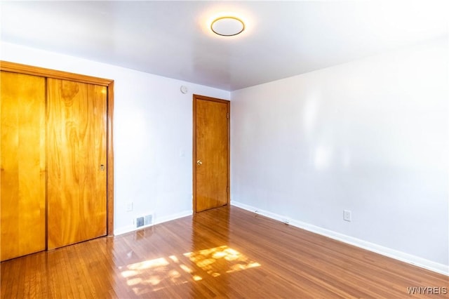 unfurnished bedroom featuring visible vents, wood finished floors, and baseboards