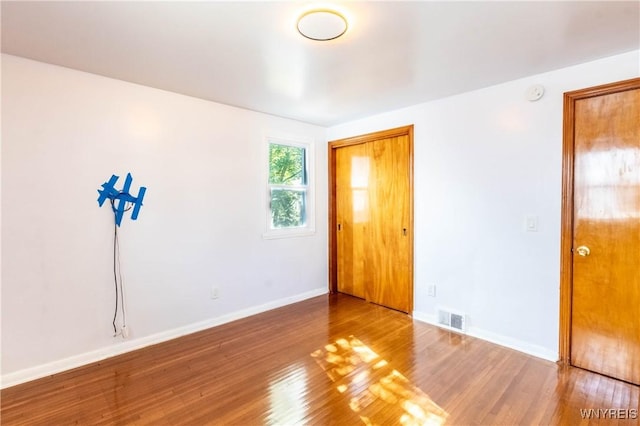 unfurnished room with visible vents, baseboards, and wood finished floors