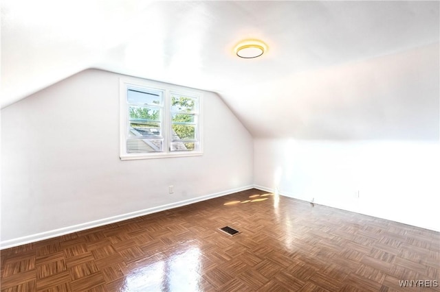 additional living space with vaulted ceiling, baseboards, and visible vents