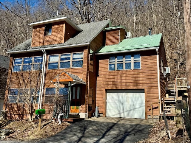 rustic home featuring a garage, stairway, and aphalt driveway