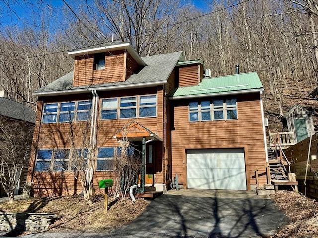 chalet / cabin with stairs, an attached garage, and driveway