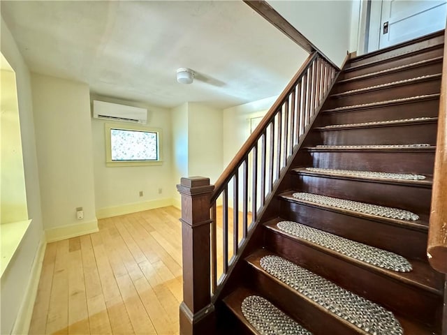 staircase with hardwood / wood-style floors, baseboards, and a wall mounted air conditioner