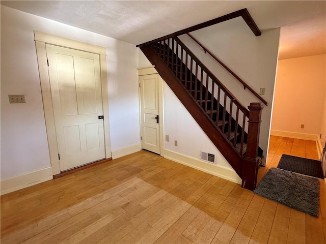 stairs with visible vents, wood-type flooring, and baseboards