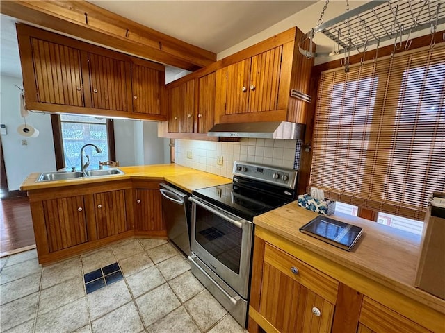 kitchen featuring visible vents, a sink, appliances with stainless steel finishes, exhaust hood, and decorative backsplash