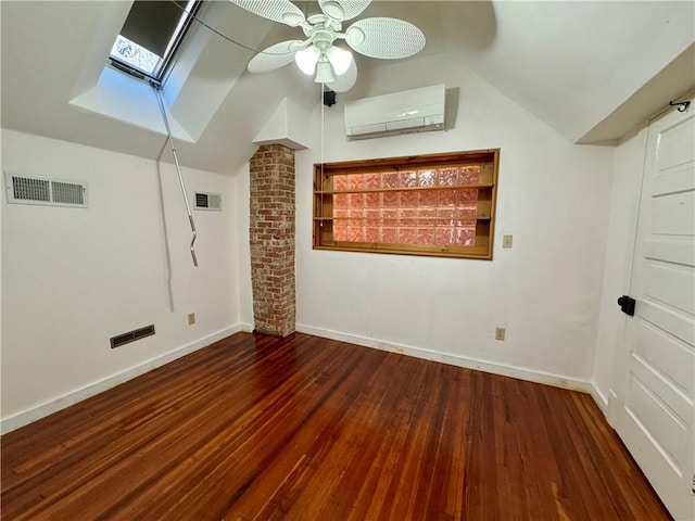 empty room featuring lofted ceiling with skylight, visible vents, an AC wall unit, and wood finished floors