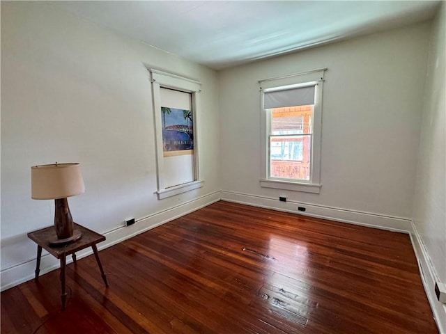 spare room featuring baseboards and hardwood / wood-style flooring