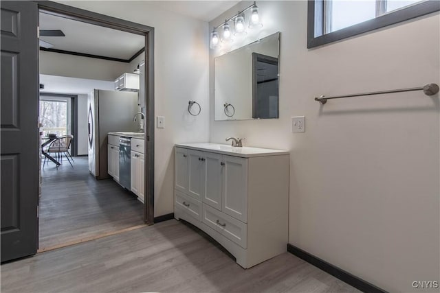 bathroom featuring baseboards, wood finished floors, vanity, and crown molding