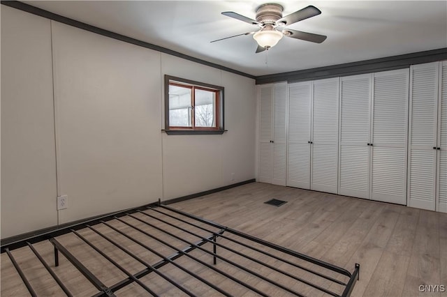 unfurnished bedroom featuring ceiling fan, visible vents, and light wood-style flooring