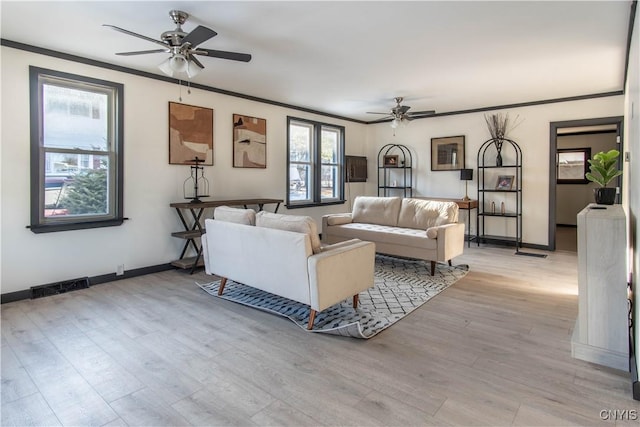 living area with light wood finished floors, visible vents, crown molding, baseboards, and a ceiling fan