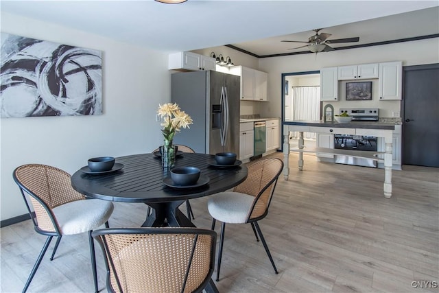 dining space with baseboards, light wood-style floors, a ceiling fan, and crown molding