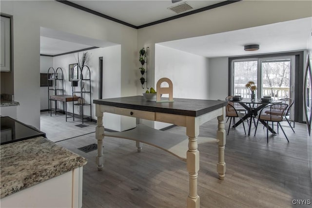 dining space featuring visible vents, crown molding, baseboards, and wood finished floors