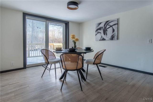 dining space with visible vents, wood finished floors, and baseboards