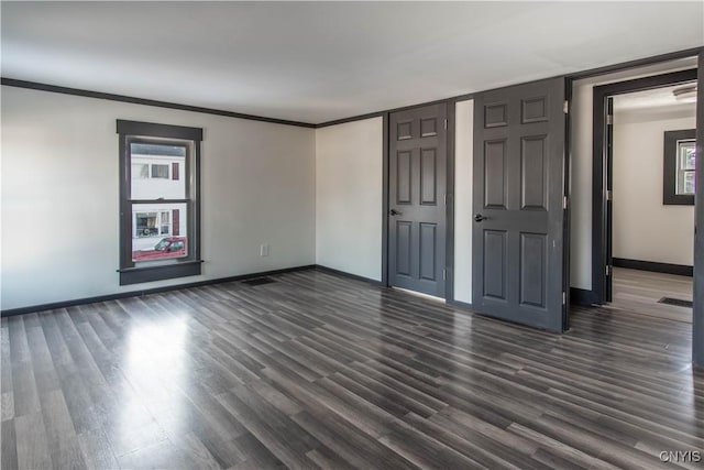 unfurnished bedroom with multiple windows, dark wood-style floors, and baseboards