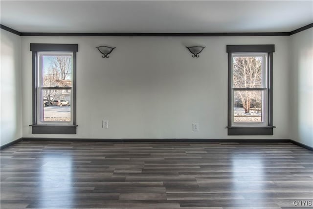 empty room with dark wood-style floors, crown molding, and baseboards