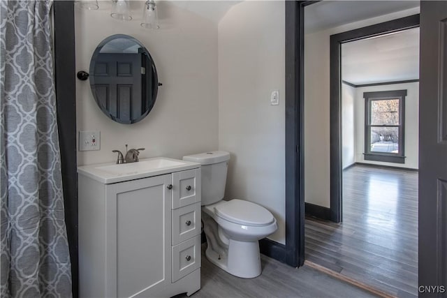 bathroom with baseboards, toilet, wood finished floors, and vanity