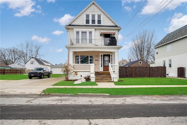 view of front of property with a balcony, covered porch, a front yard, and fence