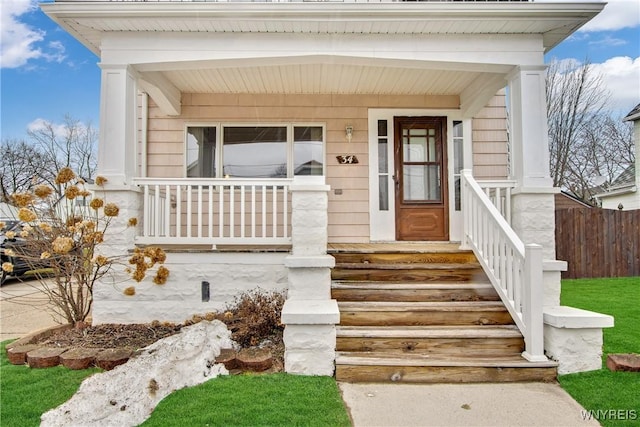 doorway to property with a porch and fence