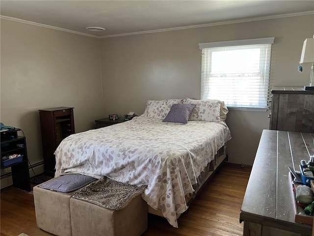 bedroom with a baseboard heating unit, wood finished floors, visible vents, and ornamental molding